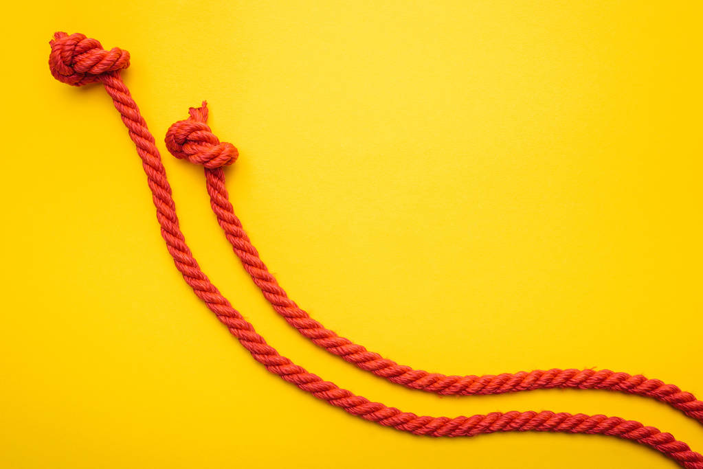 Rote Jute und lange Seile mit Knoten auf Orange  - Foto, Bild