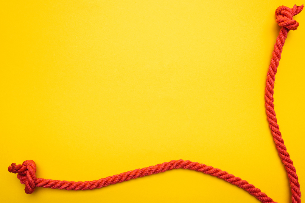 rote Jute-Seile mit Knoten isoliert auf orange  - Foto, Bild