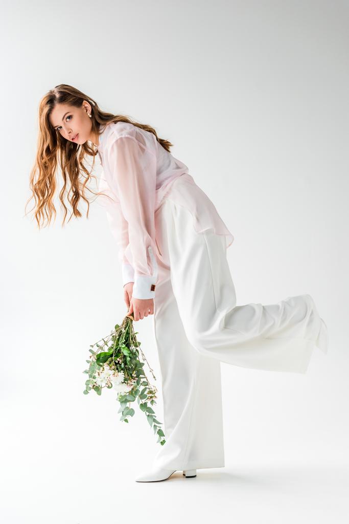 elegante giovane donna che tiene fiori con foglie di eucalipto su bianco
  - Foto, immagini