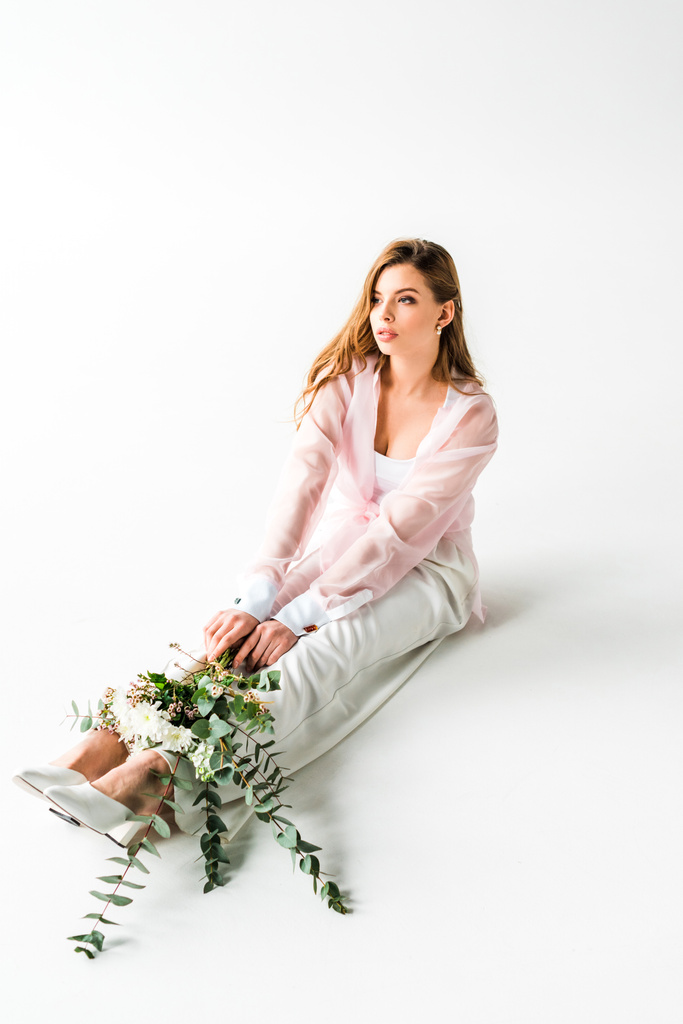 élégante jeune femme assise avec des fleurs et eucalyptus vert sur blanc
  - Photo, image