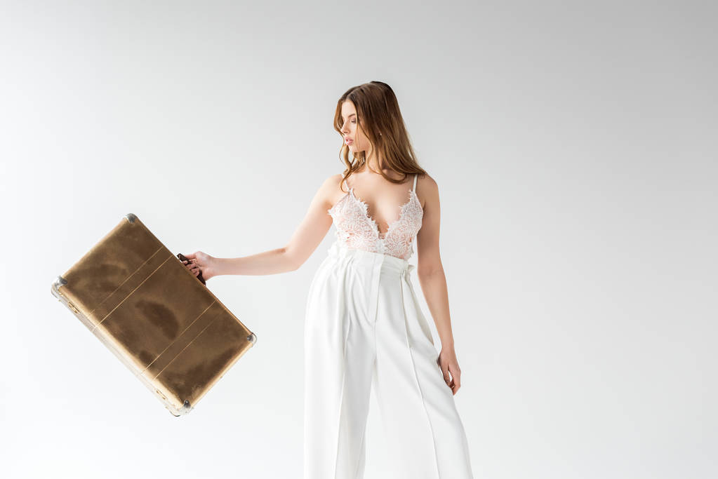 красива дівчина тримає дорожню сумку, стоячи на білому
  - Фото, зображення
