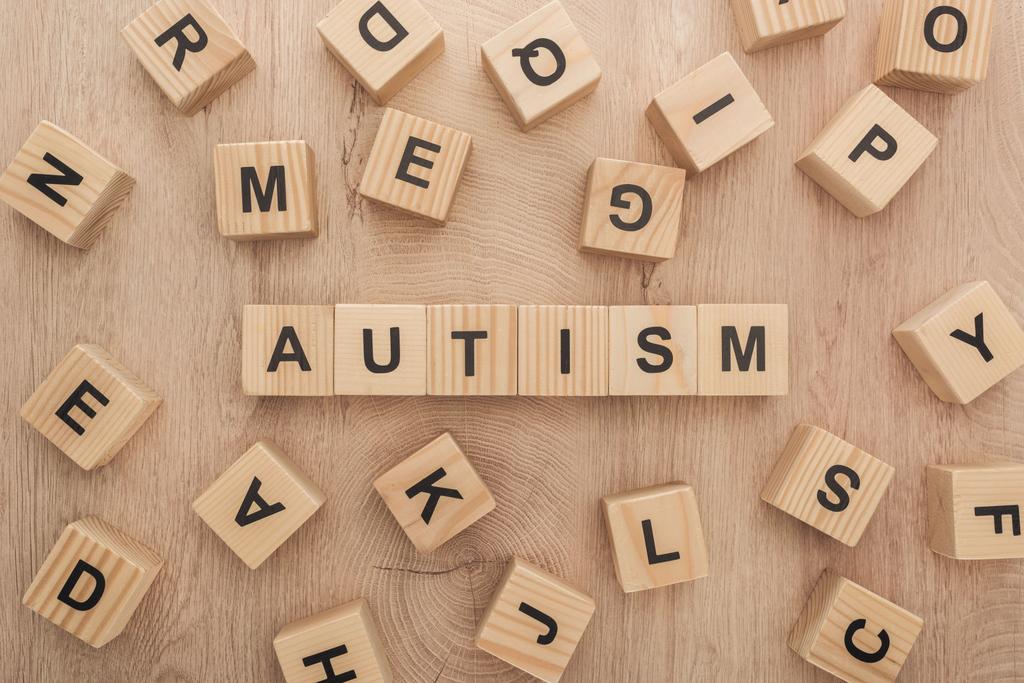 pohled shora autismu písma z dřevěných kostek s různými písmeny na dřevěný stůl - Fotografie, Obrázek