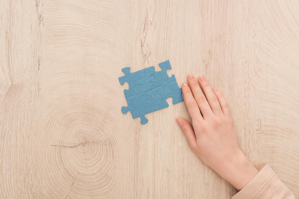 vue recadrée de la main féminine près de puzzles bleus sur table en bois
 - Photo, image