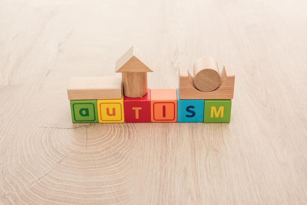 Autismus-Schriftzug aus bunten Würfeln mit Bausteinen auf Holzoberfläche - Foto, Bild