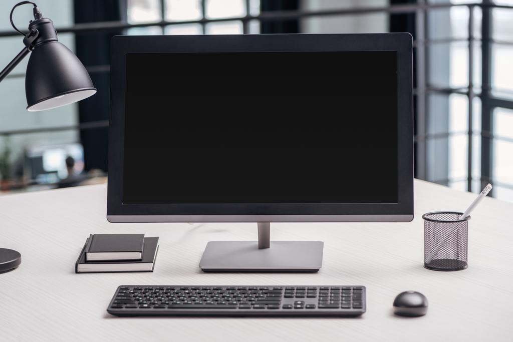 Computermonitor mit leerem Bildschirm und Schreibwaren am Arbeitsplatz - Foto, Bild
