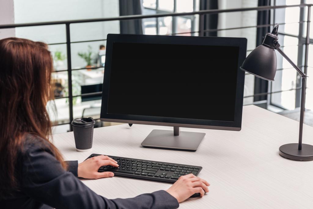 περικοπεί προβολή της γυναίκας χρησιμοποιώντας υπολογιστή στο χώρο εργασίας με φωτιστικό και καφέ να πάει στο σύγχρονο γραφείο - Φωτογραφία, εικόνα