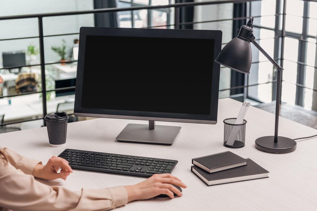 vista cortada da mulher usando o computador no local de trabalho no escritório moderno
 - Foto, Imagem