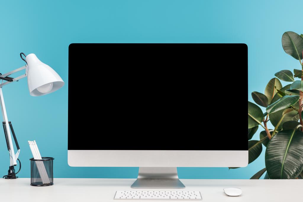 рабочее место с компьютером, лампой, канцелярскими принадлежностями на белом столе на синем фоне
 - Фото, изображение