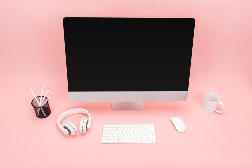 werkplek met computer, cup, hoofdtelefoons en briefpapier op roze achtergrond - Foto, afbeelding