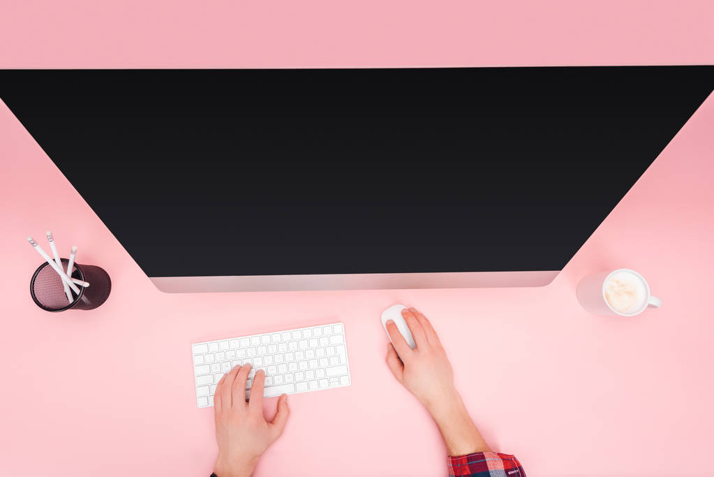ピンクの背景にコンピューターを使用している人のビューをトリミング - 写真・画像