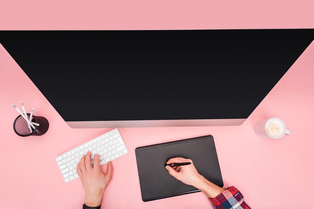 rajattu näkymä mies käyttää tietokonetta ja graafinen tabletti vaaleanpunainen tausta
 - Valokuva, kuva