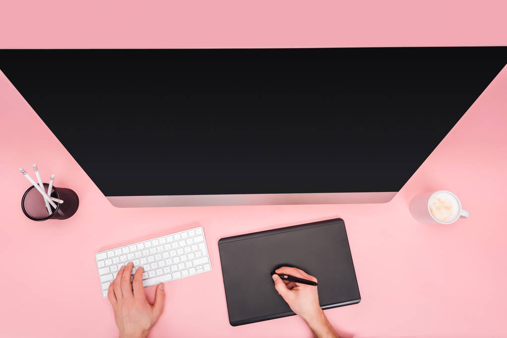 ピンクの背景にコンピューターとグラフィック タブレットを使用している人の部分的なビュー - 写真・画像