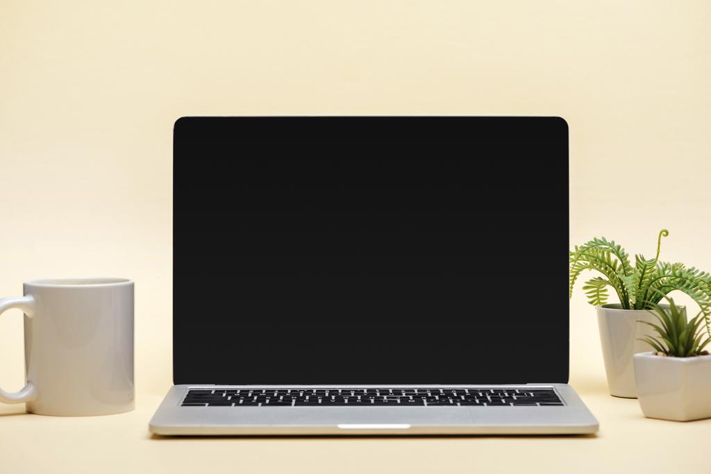 portátil con pantalla en blanco, taza y plantas verdes sobre fondo beige
 - Foto, imagen
