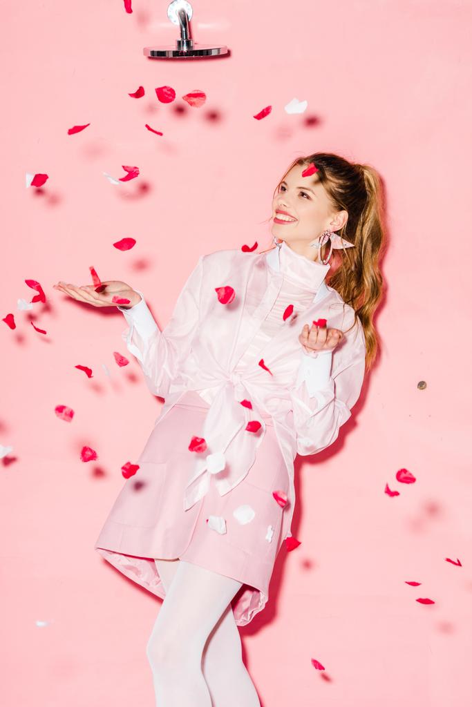  ピンクのバラの花びらの近くに立って魅力的な陽気な若い女性 - 写真・画像