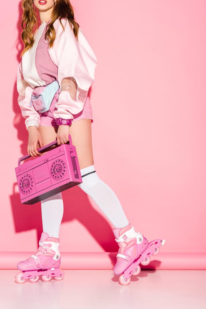 vista ritagliata di elegante ragazza in possesso retrò boombox mentre in piedi in pattini a rotelle su rosa
 - Foto, immagini