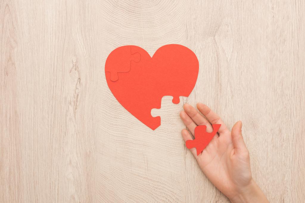 przycięte widok kobiety trzyma puzzle serca na drewnianym tle  - Zdjęcie, obraz