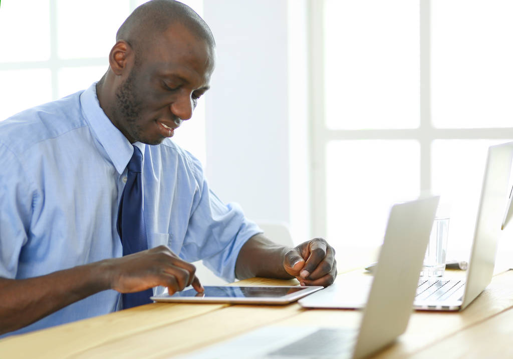 Hombre de negocios afroamericano con auriculares trabajando en su computadora portátil - Foto, imagen