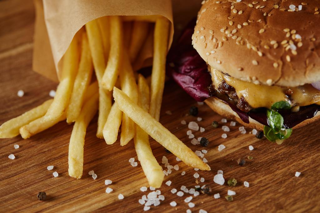 salt, french fries and delicious burger with meat on wooden surface - Photo, Image