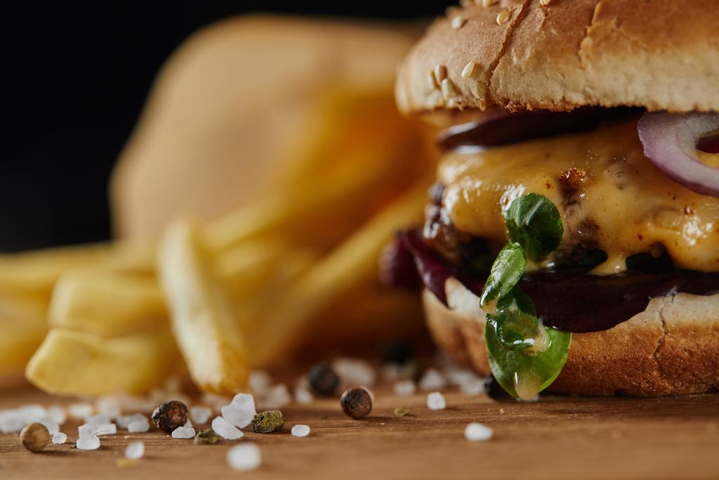 木の表面上の肉やチーズと塩とおいしいバーガーの選択的焦点 - 写真・画像