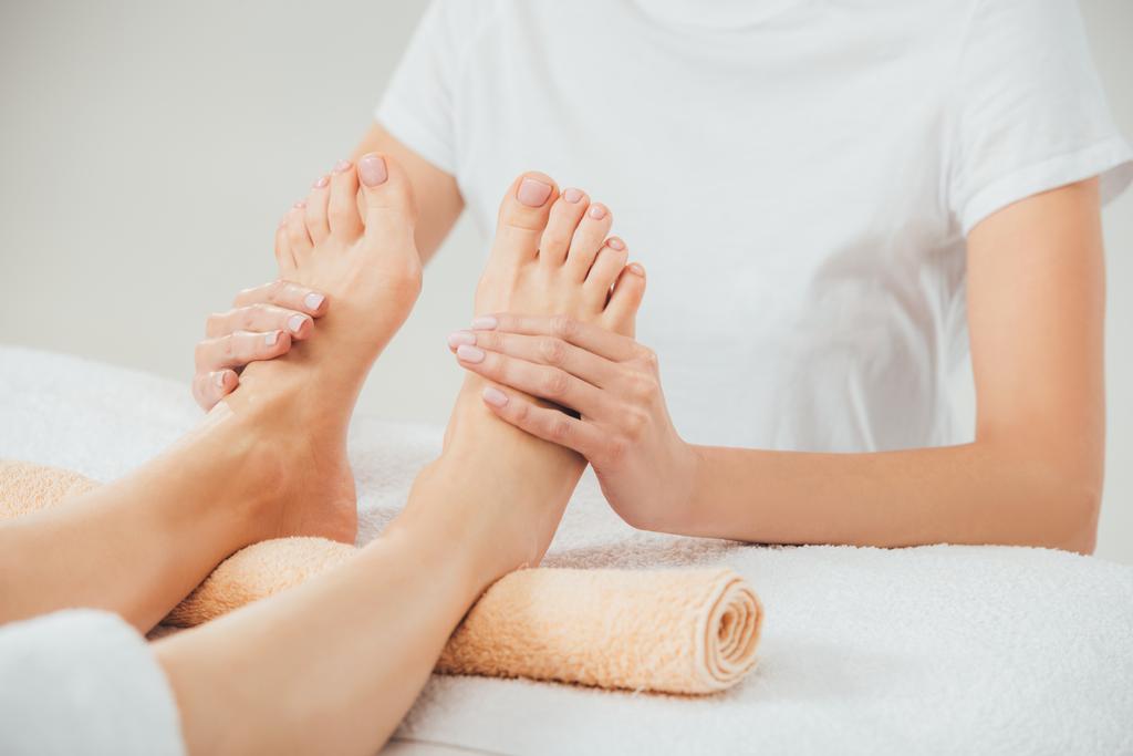 visão parcial do massagista fazendo massagem nos pés para a mulher adulta no spa
 - Foto, Imagem