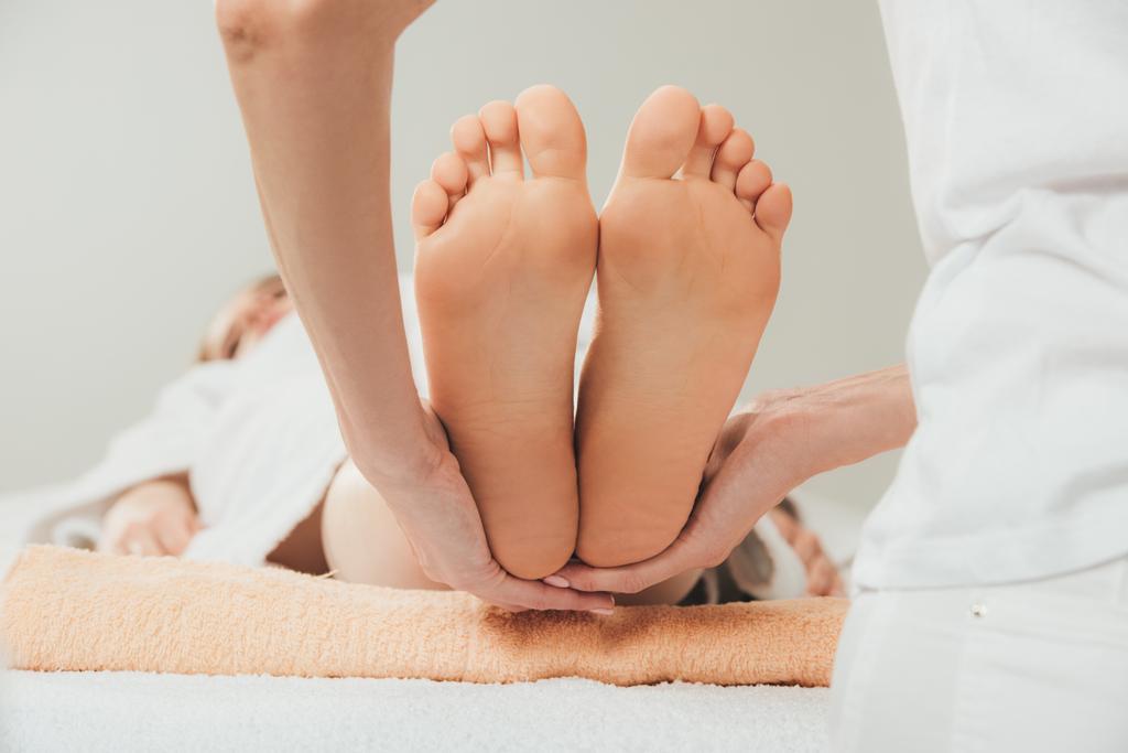 abgeschnittene Ansicht von Masseur tut Fußmassage für erwachsene Frau in Spa - Foto, Bild