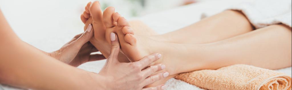 plano panorámico de masajista haciendo masaje de pies a mujer adulta en spa
 - Foto, Imagen