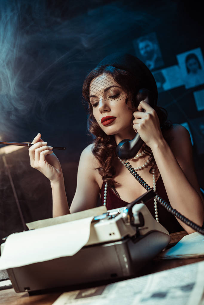 Mulher atraente com bocal falando no telefone no escritório escuro
 - Foto, Imagem