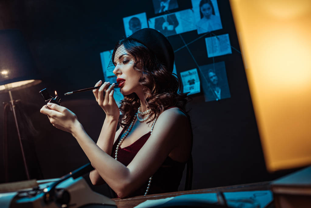 schöne Frau mit Mundstück zündet sich Zigarette im dunklen Büro an - Foto, Bild