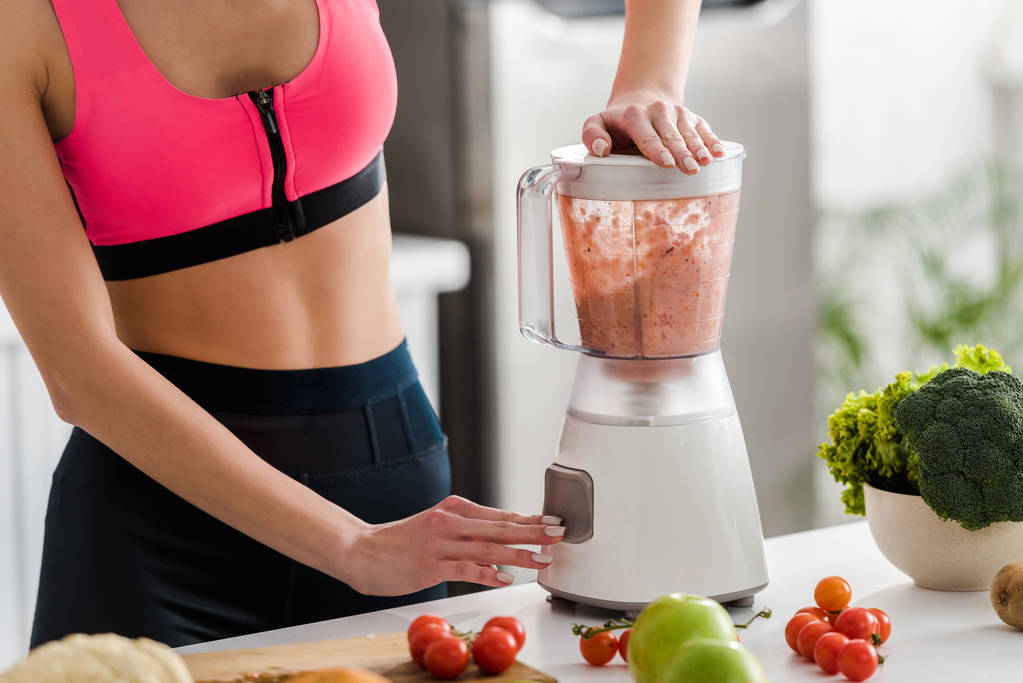 cropped view of sportswoman preparing smoothie in blender  - Photo, Image