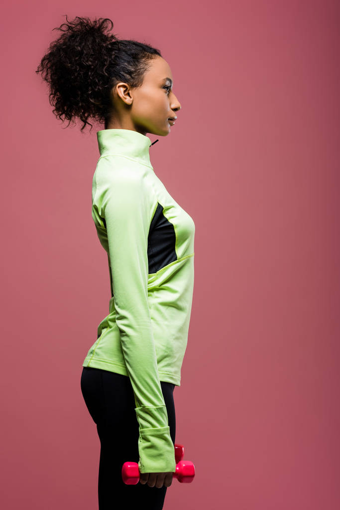 Zijaanzicht van prachtige Afrikaanse Amerikaanse Sportvrouw houdt van halter geïsoleerd op brown - Foto, afbeelding