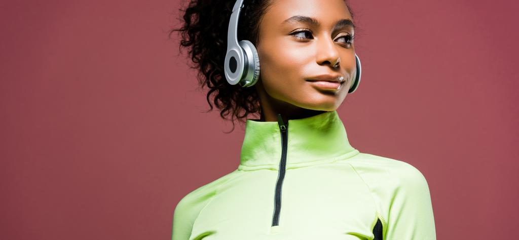 plano panorámico de la hermosa deportista afroamericana en auriculares aislados en marrón con espacio de copia
 - Foto, imagen