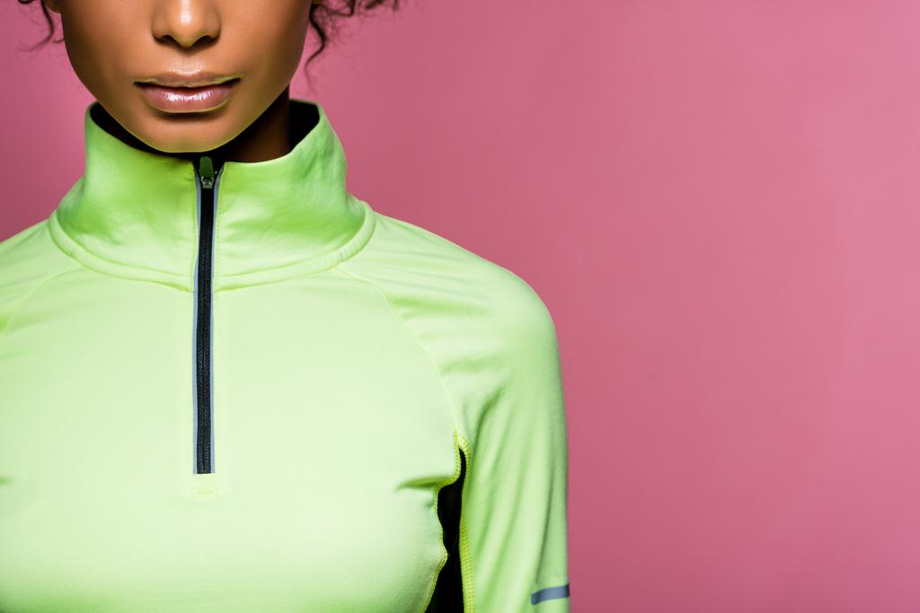 vista parziale della sportiva afroamericana in giacca da pista in posa isolata su rosa con spazio copia
 - Foto, immagini