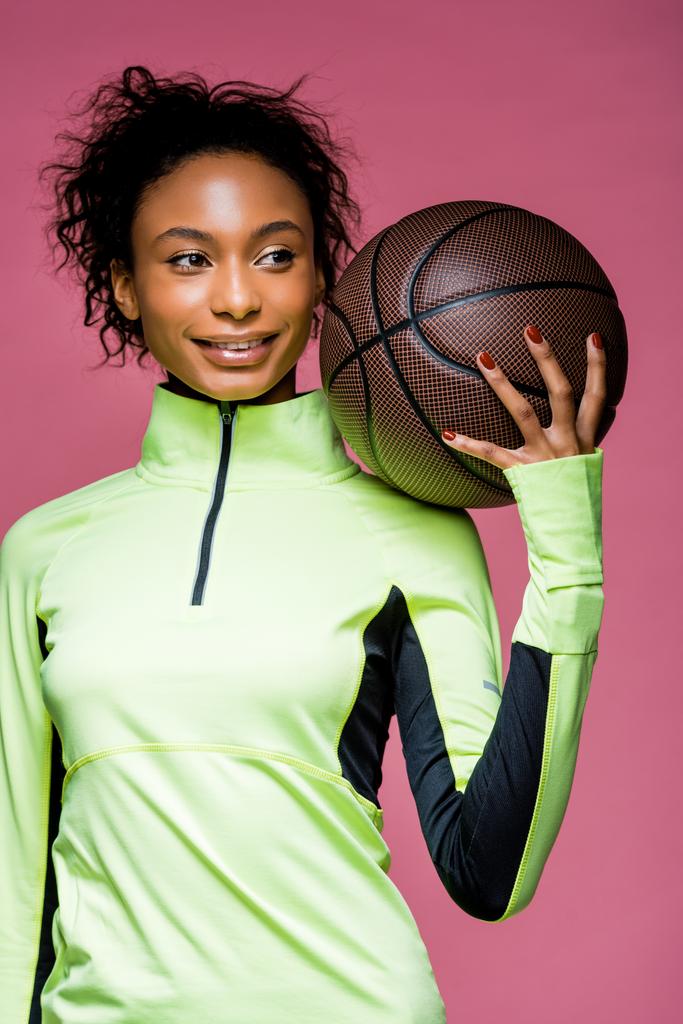 piękny uśmiechający się sportsmenka Afryki amerykański holding koszykówki na różowym tle - Zdjęcie, obraz