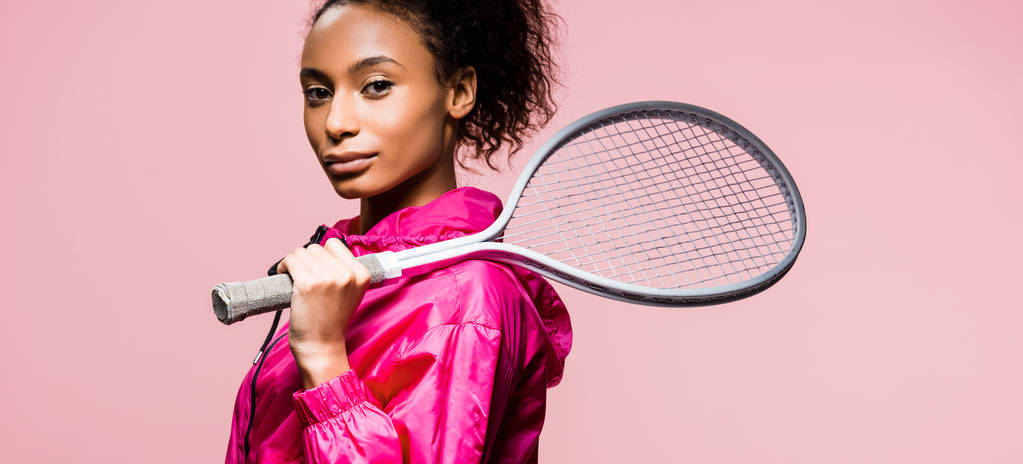 Panoramaaufnahme der schönen afrikanisch-amerikanischen Sportlerin mit Tennisschläger isoliert auf rosa  - Foto, Bild