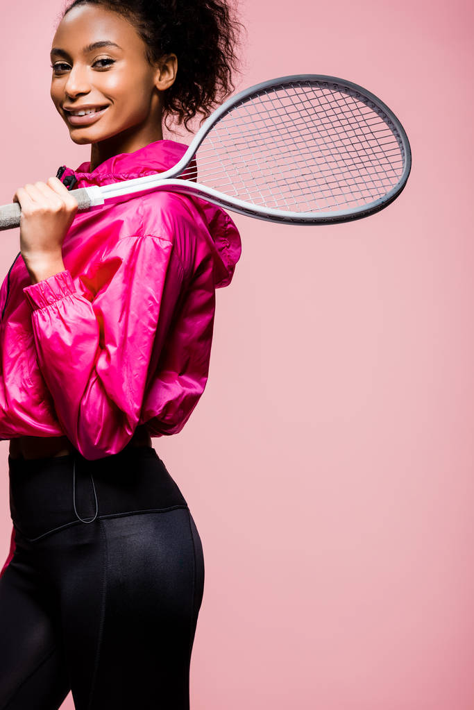 ピンクの美しいアフリカ系アメリカ人スポーツ選手のテニス ラケットを持つポーズをしながらのカメラ目線が分離されました ロイヤリティフリー写真 画像素材