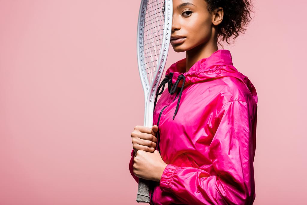 szép afro-amerikai sportoló, látszó-on fényképezőgép, és a gazdaság elszigetelt rózsaszín, másol hely teniszütő - Fotó, kép
