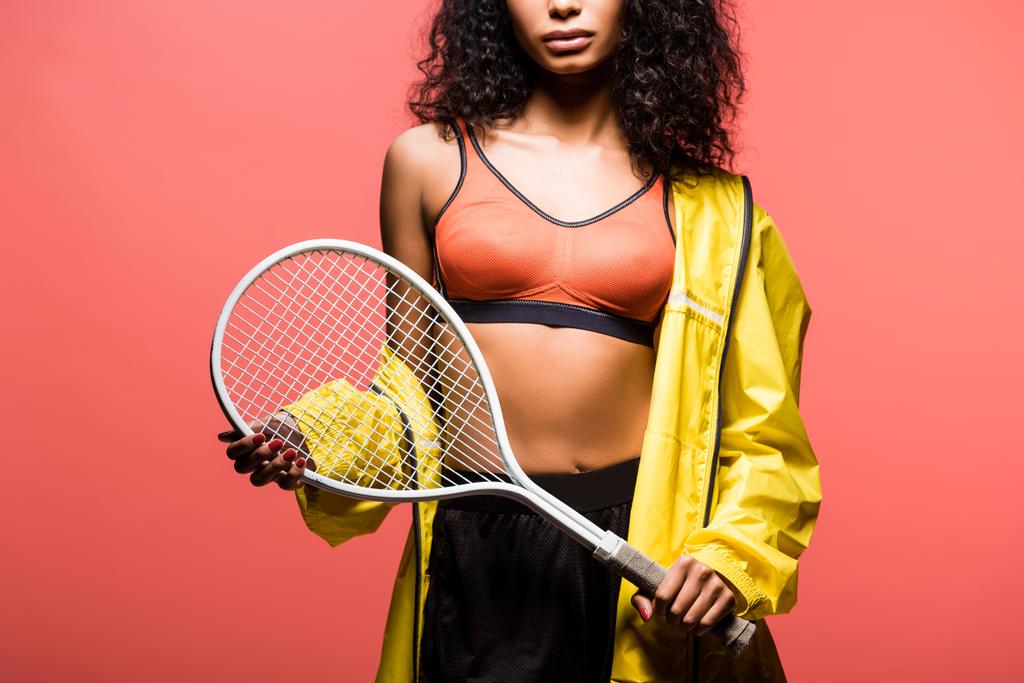 обрезанный вид на африканскую американскую спортсменку, держащую теннисную ракетку изолированную на кораллах
 - Фото, изображение