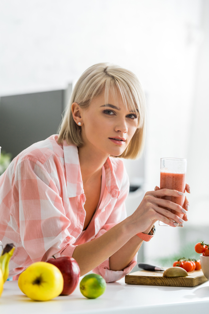 mulher atraente segurando vidro com smoothie na cozinha
  - Foto, Imagem