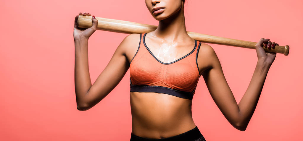panoramic shot of african american sportswoman posing with baseball bat isolated on coral  - Photo, Image