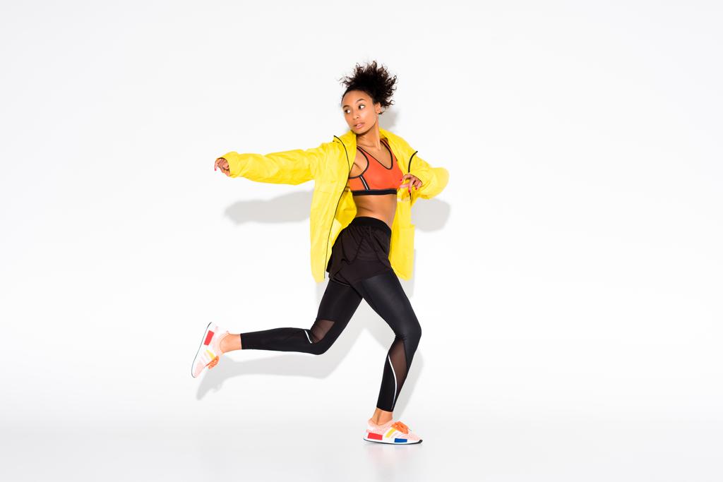 athletic african american sportswoman in yellow sports jacket running on white - Photo, Image