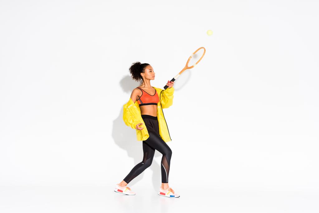 atletica sportiva afroamericana che si esercita con racchetta da tennis e palla su bianco
  - Foto, immagini