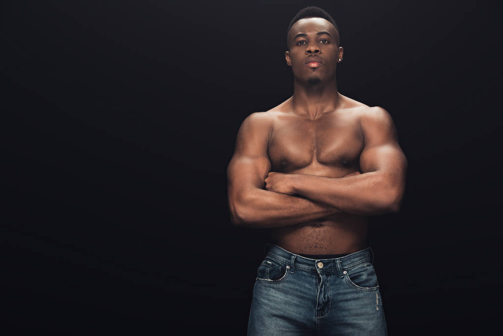 sexy muscular african american man in denim with crossed arms looking at camera isolated on black - Photo, Image
