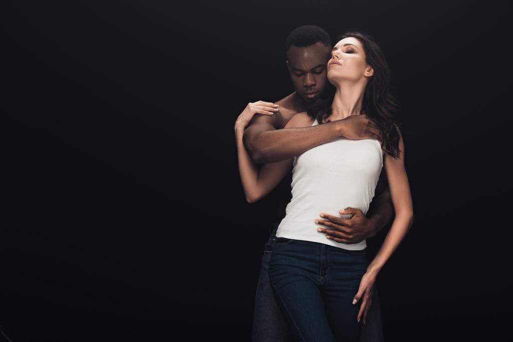 homem americano africano abraçando mulher atraente isolado em preto com espaço de cópia
 - Foto, Imagem