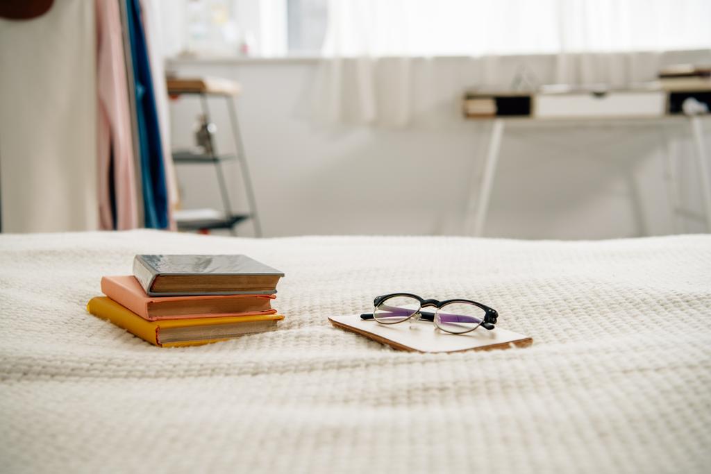 Livros e óculos na cama no quarto aconchegante claro
 - Foto, Imagem