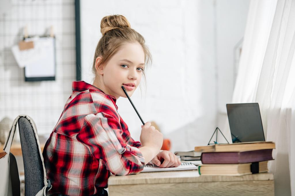 Pokovený teenager v kostce přidržující pero u stolu při práci s úkoly - Fotografie, Obrázek