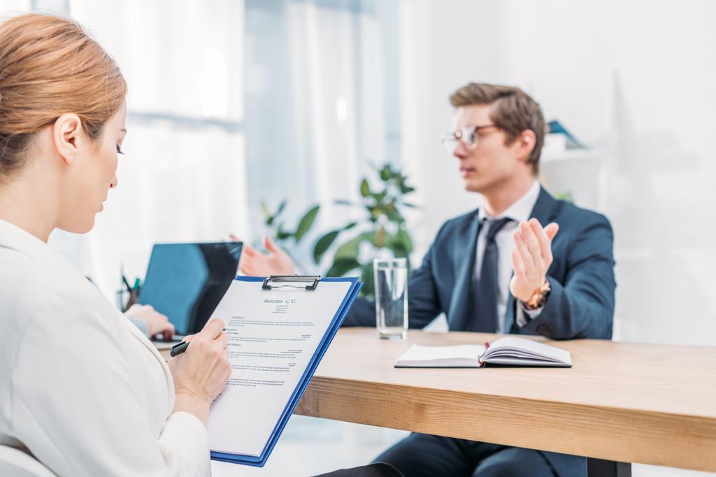 selective focus of recruiter writing on clipboard near man talking on job interview  - Photo, Image