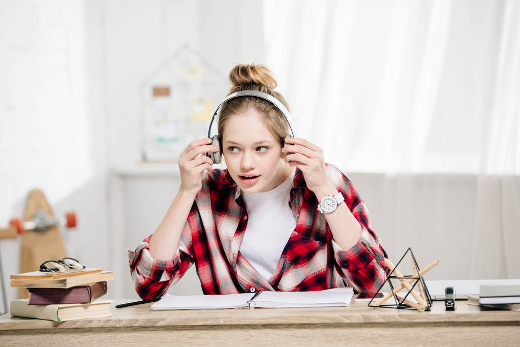 Радісна дитина-підліток у червоній картатій сорочці, що слухає музику в навушниках
 - Фото, зображення
