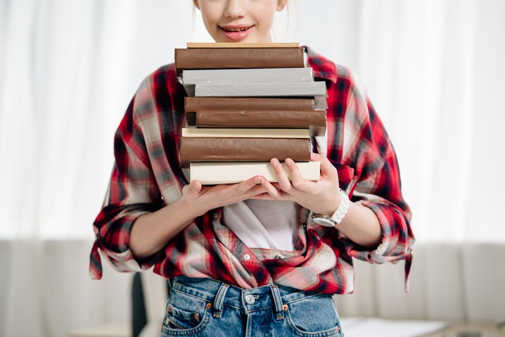 Vista cortada de adolescente em vermelho xadrez camisa segurando livros em casa
 - Foto, Imagem