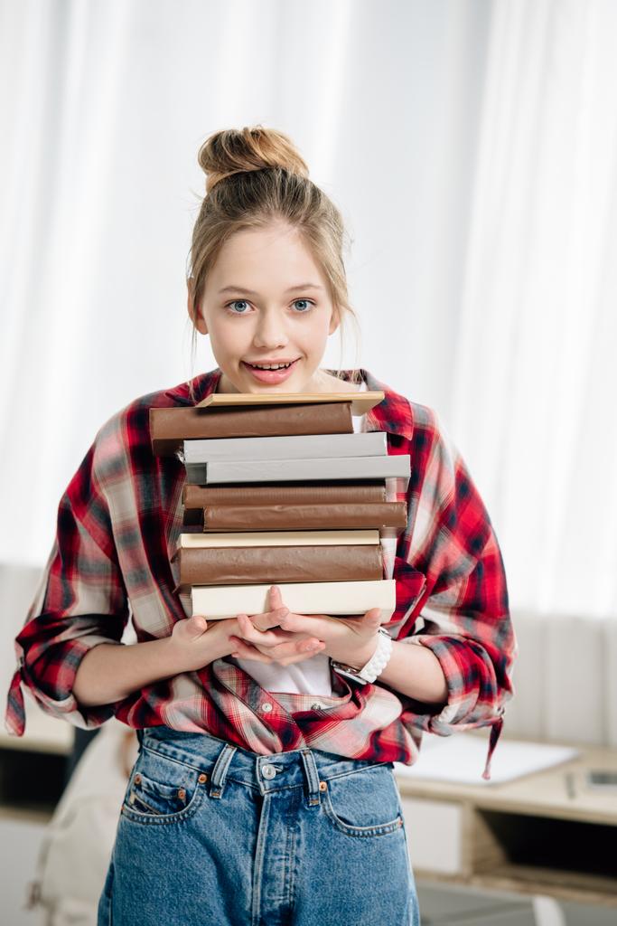 Teenage kid in red checkered shirt holding books at home - Photo, Image