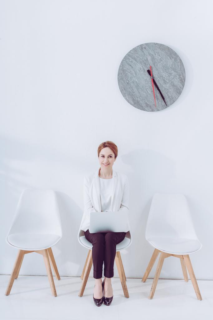 employé joyeux assis sur la chaise avec ordinateur portable en attendant entrevue d'emploi
  - Photo, image